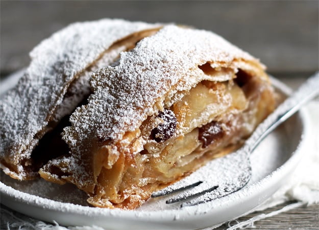 image of the apfelstrudel with powder sugar covered served on a plate with a cake fork